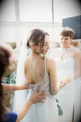 Bride getting helped into her dress