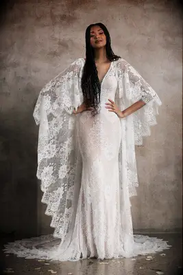 Boho lace wedding gown with plunging neckline and scalloped cape