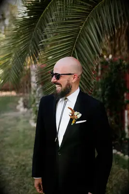Man wearing black suit with gold embellished bolo tie