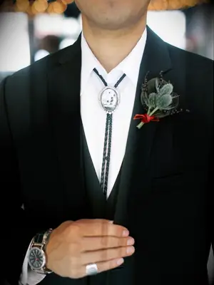 Groom wearing custom white buffalo turquoise bolo tie with black suit