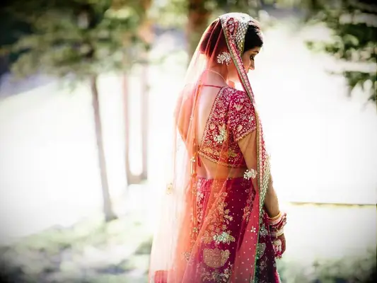Bride wearing red lehenga with sheer veil