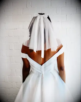 Model wears a beautiful veil with a bow attached. 