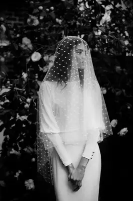 Model wears a finger-tip length veil with a polka-dot pattern. 