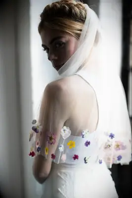 Model wears a beautiful sheer veil with flowers stitched on the trim. 