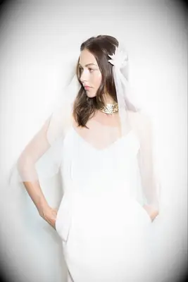 Model wears a beautiful veil with feathered detailing. 