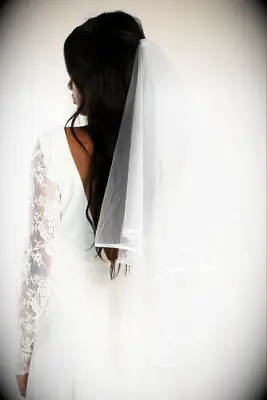 Model wears a sheer veil with satin trim. 