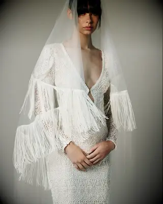 Model wears a sheer veil with a fringed hem. 