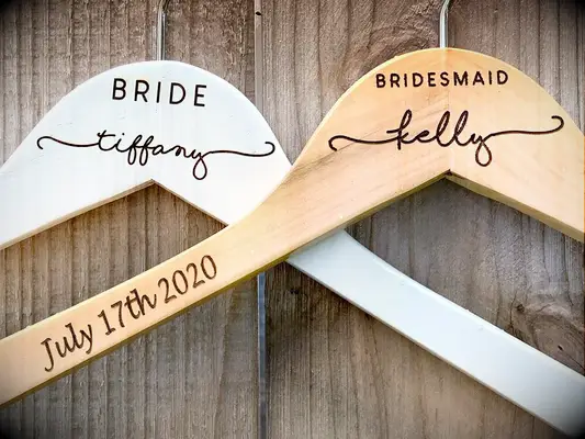Wooden and white hangers with title engraved in minimalist font, name in calligraphy and wedding date