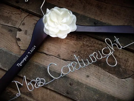 Wooden hanger with future title and last name in silver wire and white flower