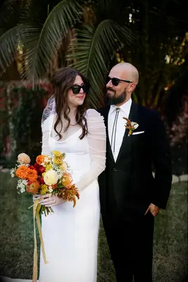 Bride With Bright Bouquet and Groom With Bolo Tie Posing in Sunglasses at Casual Wedding