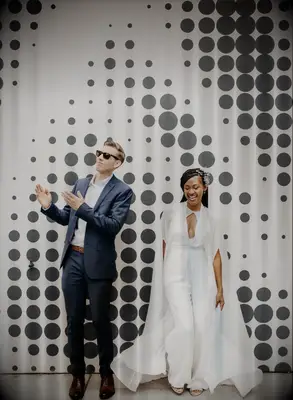 bride wearing a white jumpsuit and groom wearing blue suit