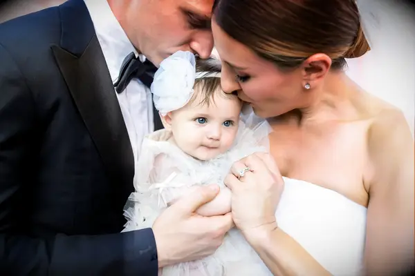 A bride and groom kiss their little girl