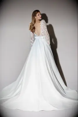 Model wears a dress with an open back and bow, best bow wedding dresses 2024. 