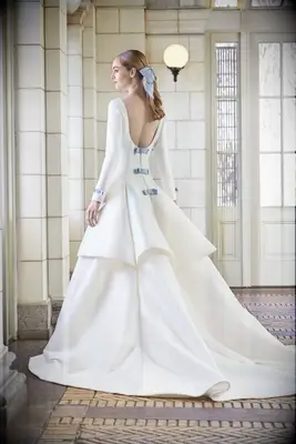 White wedding dress with an open back and blue bow detailing.