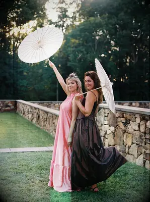 Wedding guests wearing long dresses and sun umbrellas