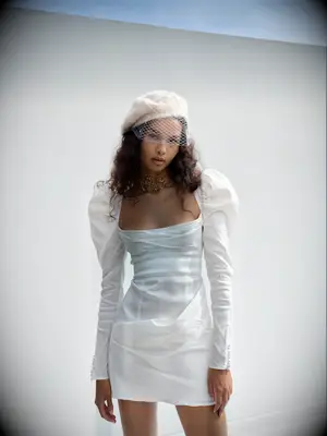 Model wears a chic white mini dress with puffed sleeves. 