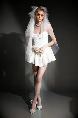 Model wears a corset-style white mini dress. 