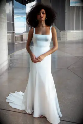 Model wears a white gown with a square neckline. 