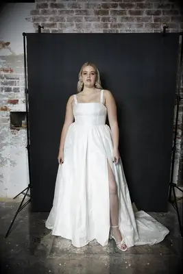 Model wears a silk wedding dress with a square neckline. 