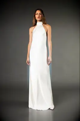 Model wears a long silk dress with a halter neckline. 