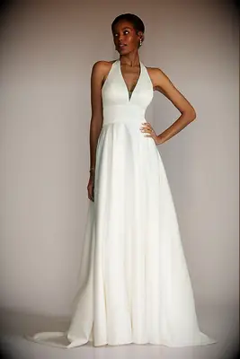 Model wears an elegant white wedding dress with a halter neckline. 