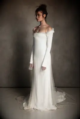 Model wears an elegant white dress with tulle detailing. 