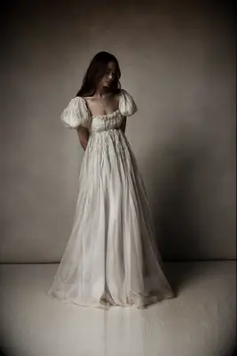 Model wears a wedding gown with puffed sleeves. 