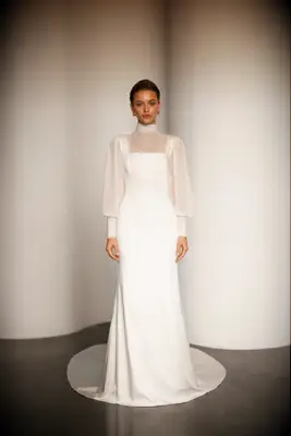 Model wears an elegant wedding dress with long and sheer puffed sleeves. 