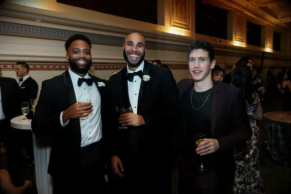 Guests wearing black tuxes and maroon blazer and trousers