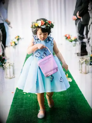 Flower girl walking down the aisle in blue flower girl outfit covered in butterflies.