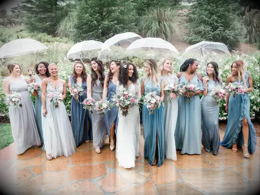 Bride and bridesmaids in blue dresses holding umbrellas