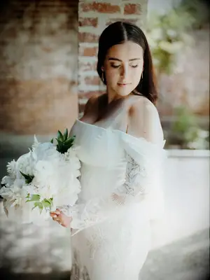 Bride wearing a white, off the shoulder lace wedding dress holding a bouquet