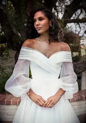 Bride wearing a white long sleeve off the shoulder wedding dress made out of organza fabric
