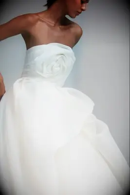 Bride wearing a white, strapless gazar wedding down with rose detail
