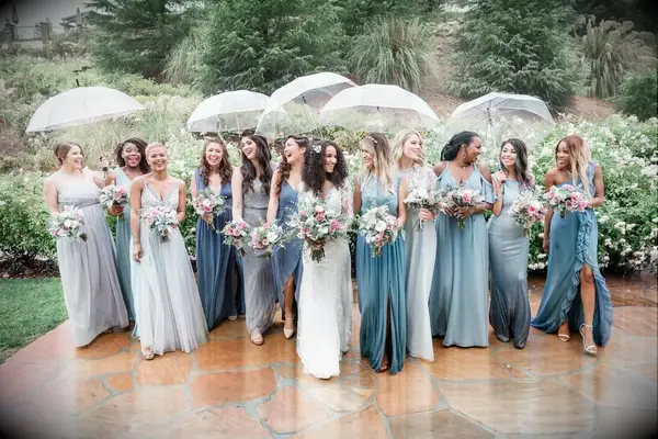 A bride smiles with her bridesmaids beneath clear umbrellas.
