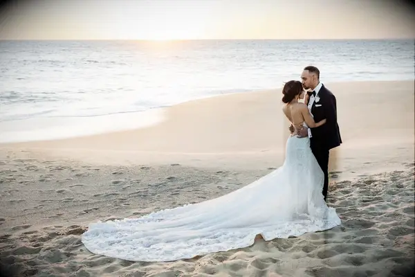Bride and groom on the beach with long royal wedding dress train