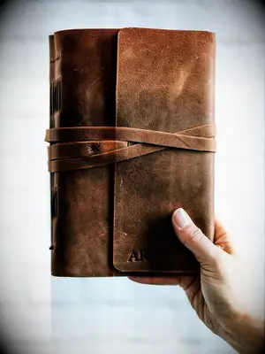 Brown leather notebook stamped with initials traditional third anniversary gift