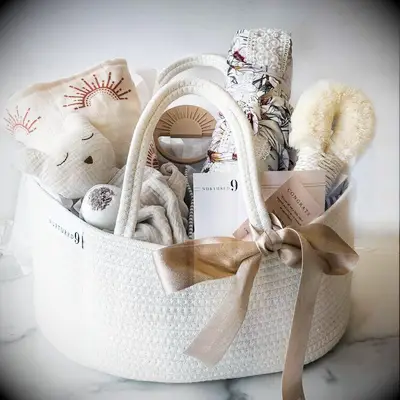 White woven basket with baby toys, blankets and a notepad gift for pregnant wife