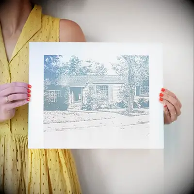 Woman holds a custom print that depicts a house. 