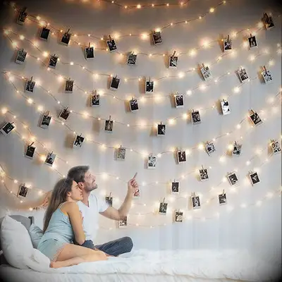 Couple gazes at photos strung on lights. 