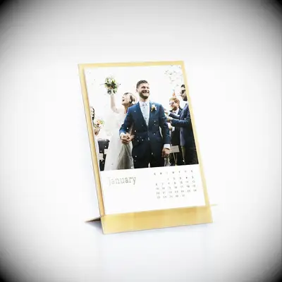 Gold calender gift displays a photo of a couple at their wedding. 