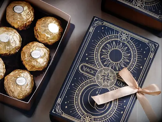 Dark blue Magic Diary box with gold intricate design holding gold wrapped candies