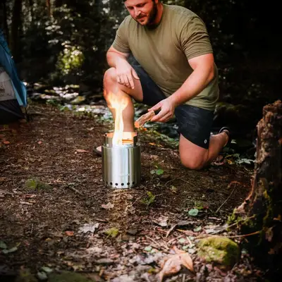 Man uses a portable campfire stove in the wilderness anniversary gift for him