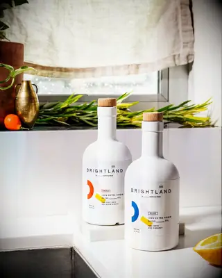 Two bottles of gourmet olive oil sit on a counter top. 