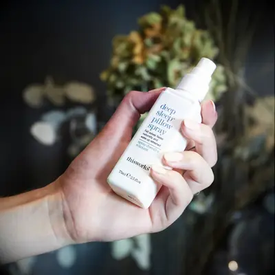 Person holds a bottle of sleep-inducing pillow spray. 