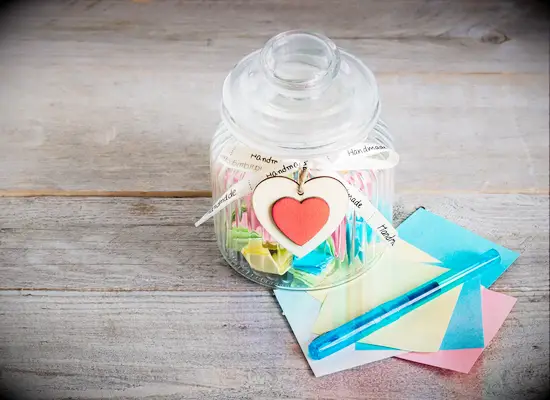 Clear jar filled with date ideas on colorful paper for DIY anniversary gift