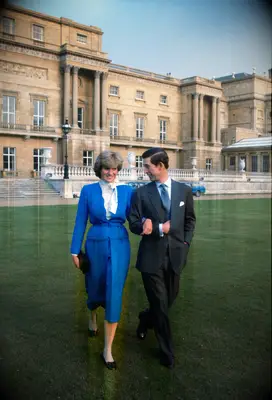 Diana and Charles walk arm in arm across a beautiful green lawn. 