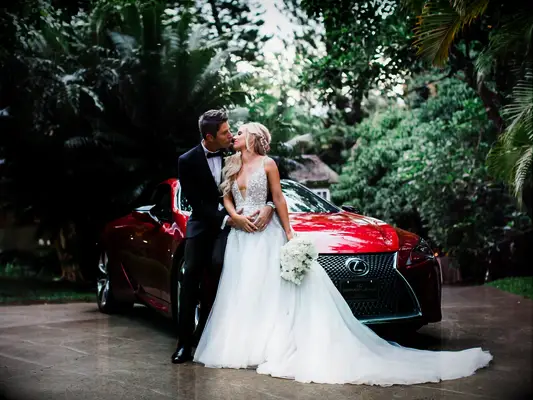 Lauren and Arie with a red sports car on their wedding day
