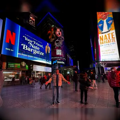 Nate Bargatze standing in front of two of his billboards 