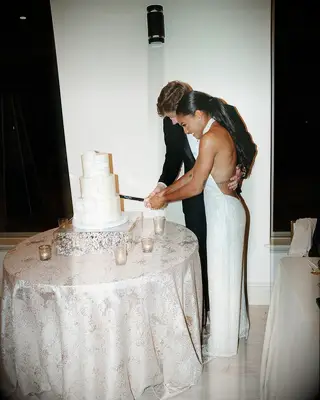 Tara Davis and Hunter Woodhall cutting the cake at their wedding